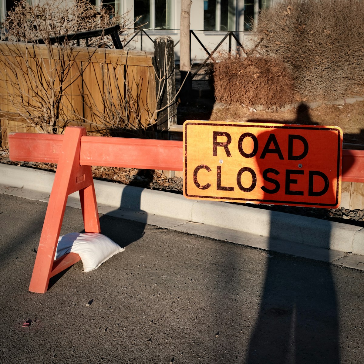 Orange road closed barrier with shadow on asphalt